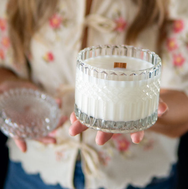 Woman holding a candle in a glass vessel with lid with a blurred background